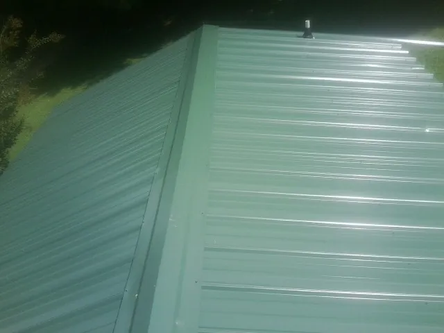 New green metal panels meeting at the ridge of a roof — Flat Roof Repair work by our crew in Paramount