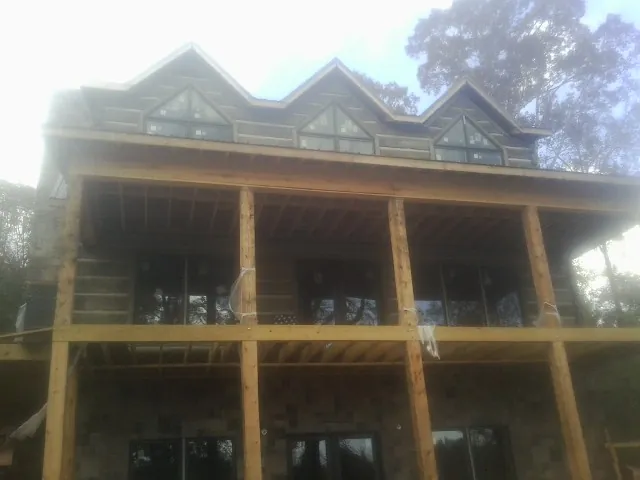 Dormers and porch framing on a large log home under construction — Roof Coating work by our crew in Paramount