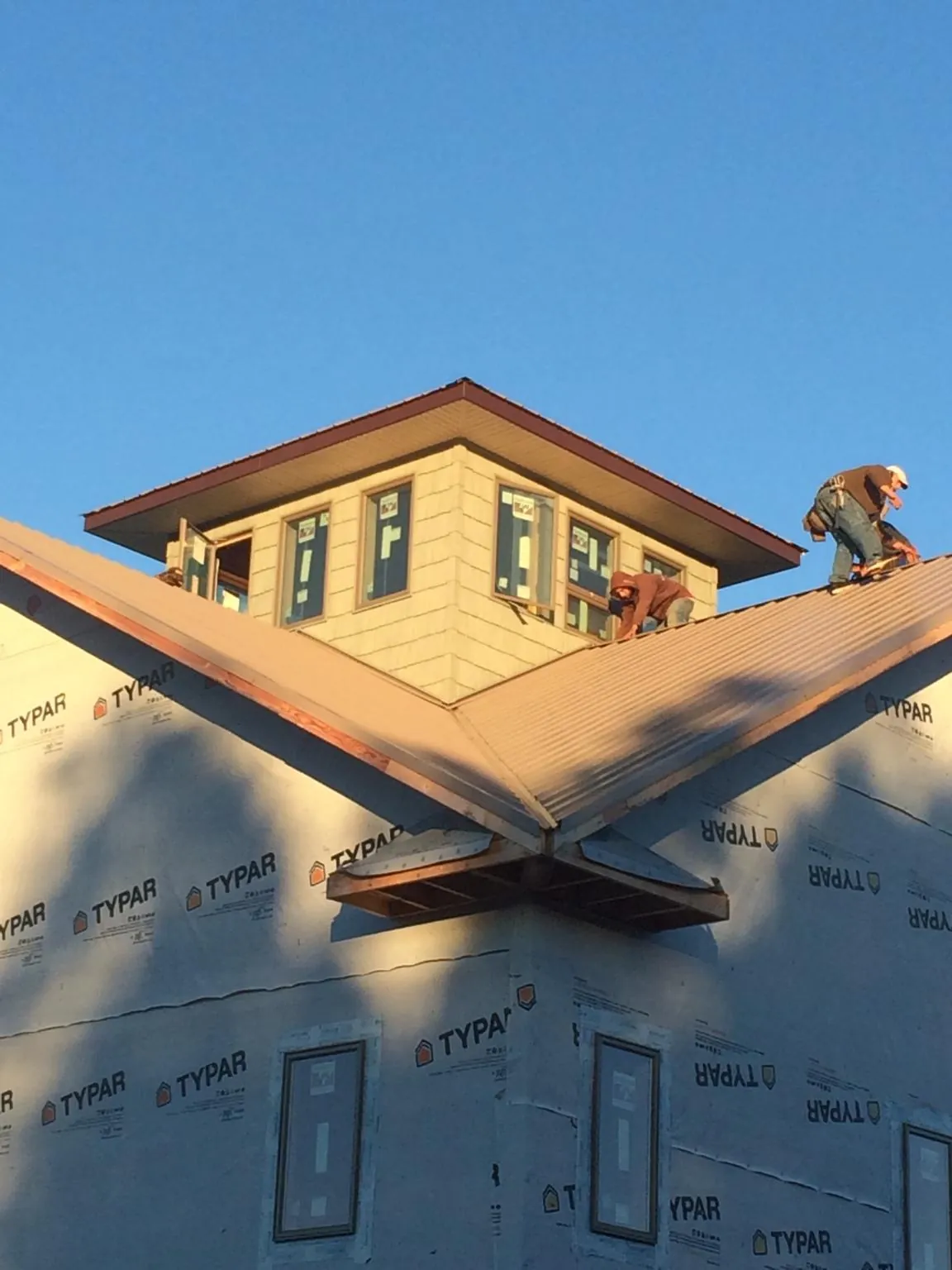 Roofers working around a rooftop cupola on a new metal roof at sunset — Roof Waterproofing in Paramount by Roofing Brothers